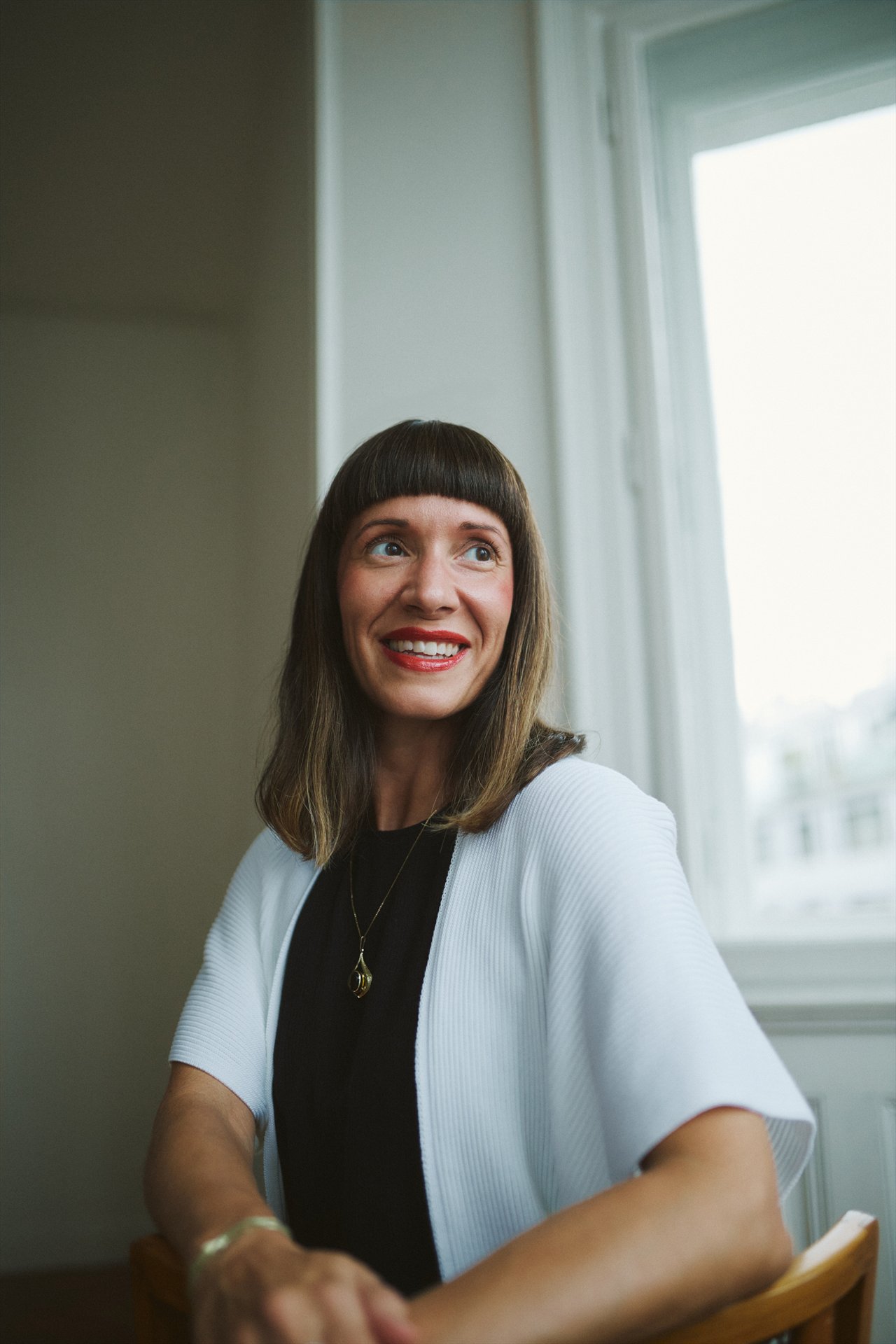 Nadja Horesovsky sitzt lächelnd am Fenster, in einer hellen Strickjacke.